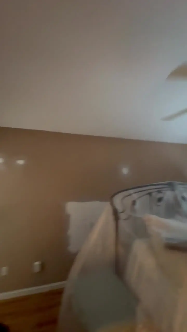 Bedroom mid-project with primer patches on the walls and furniture covered in protective plastic