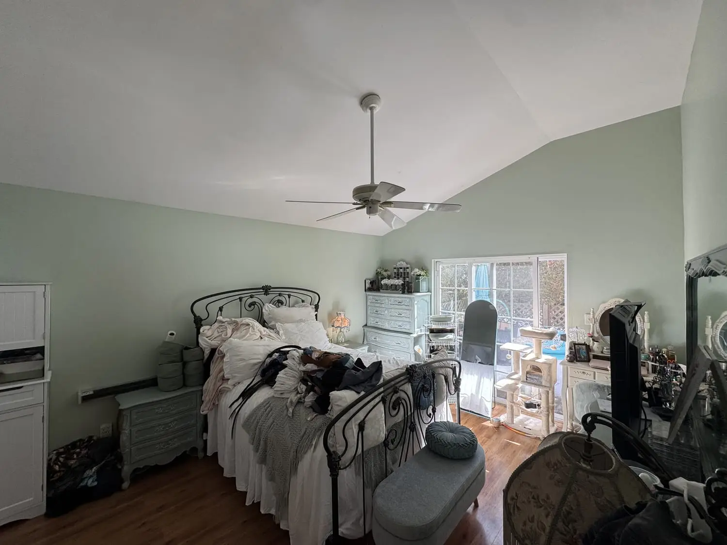 Bedroom painted in a soft sage green with white trim and natural light