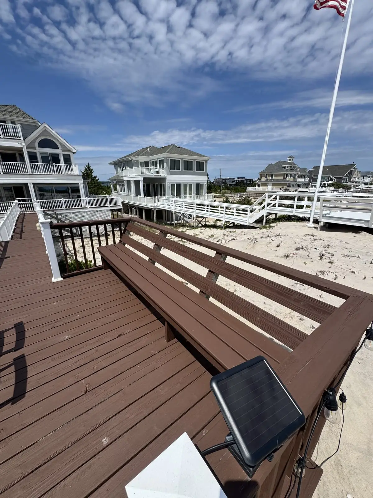 Freshly stained waterfront deck among Hamptons beach homes under a blue sky