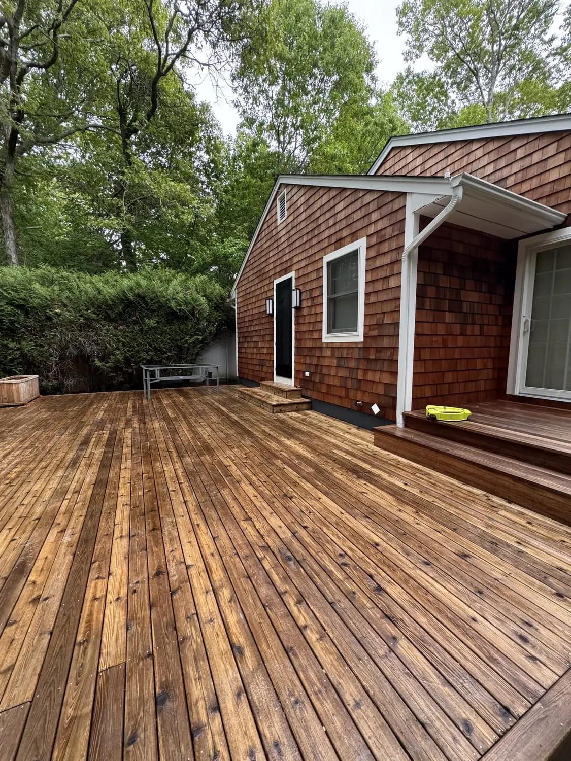 Freshly stained wooden deck with rich, even colour beside a shingled home