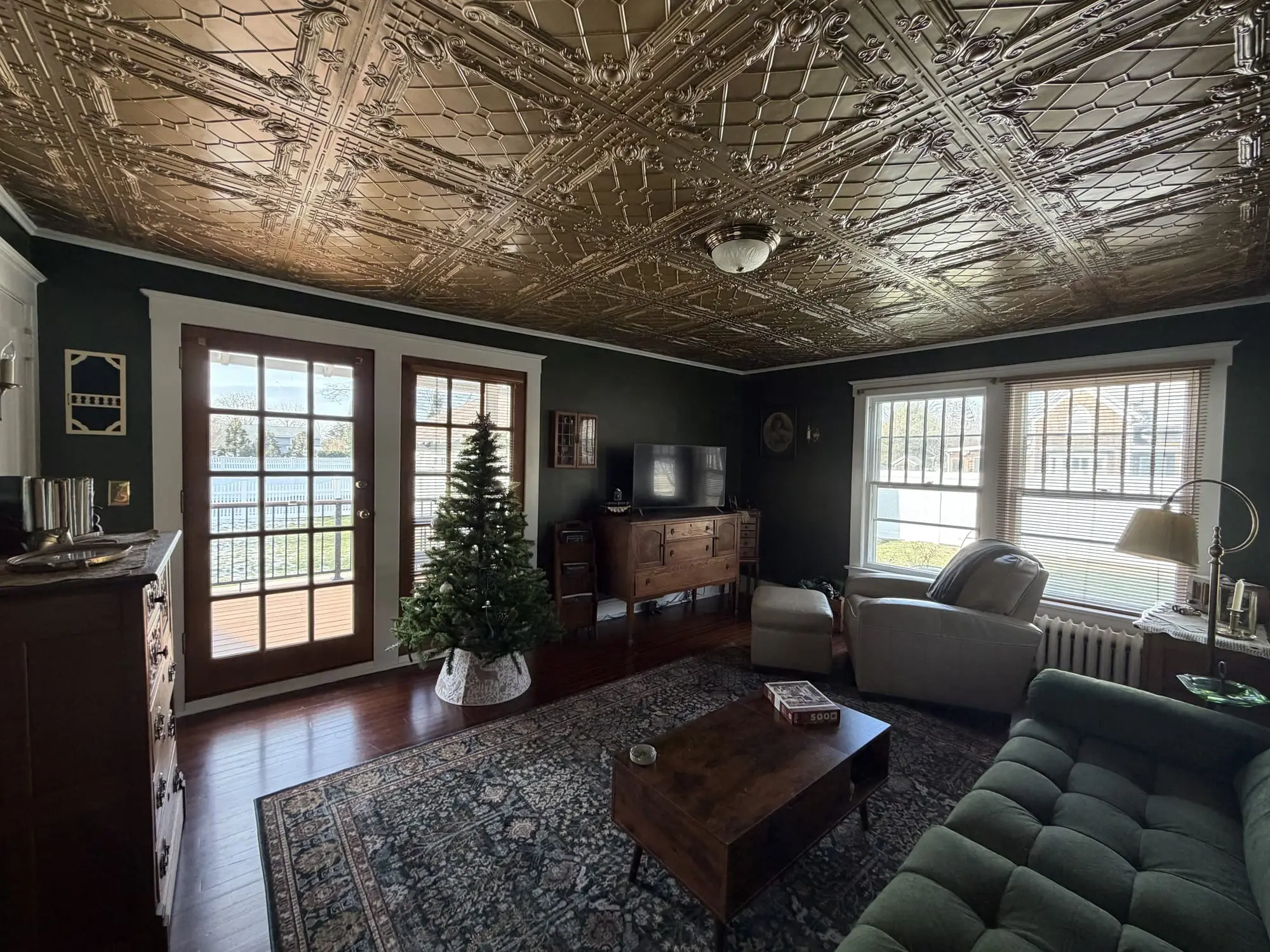Elegant dark-green living room with an ornate tin ceiling, freshly painted by Finesse Finish