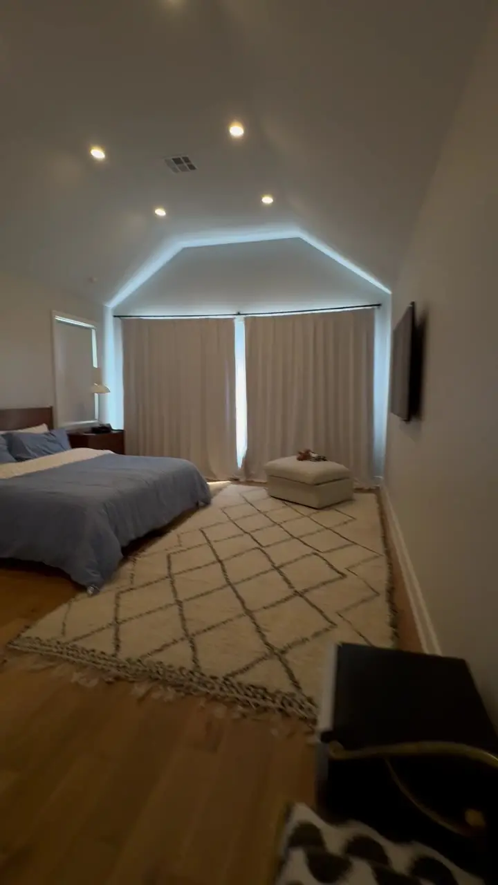 Spacious master bedroom with a vaulted ceiling, freshly painted walls and warm evening light