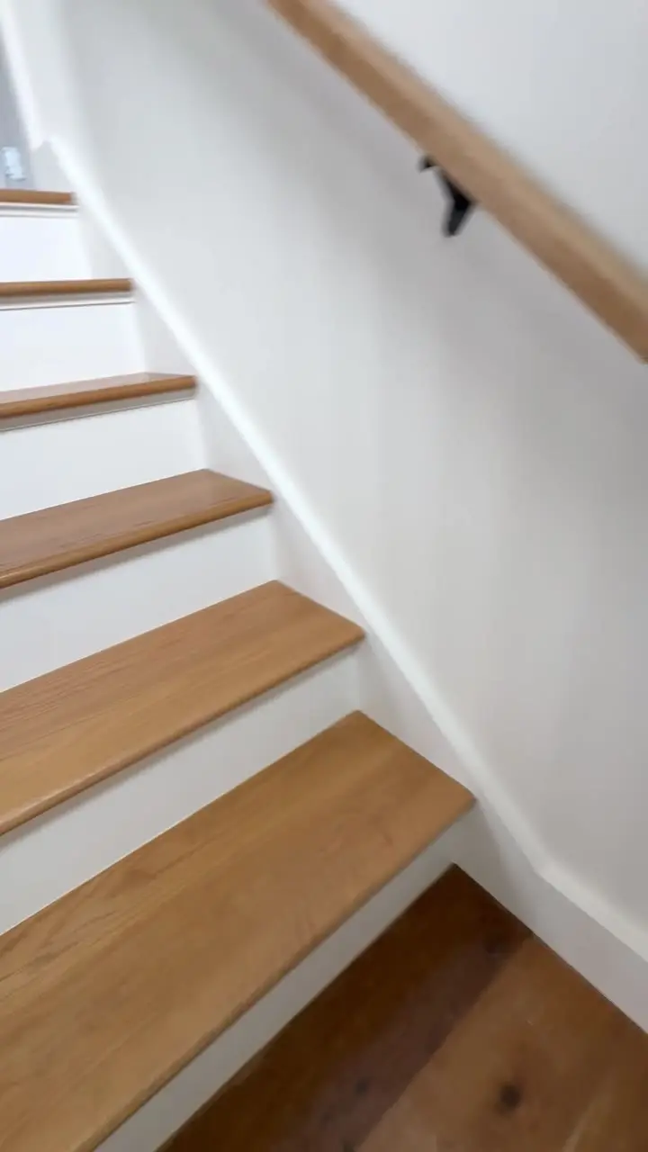 Staircase with freshly painted white risers, oak treads, black spindles and an oak handrail